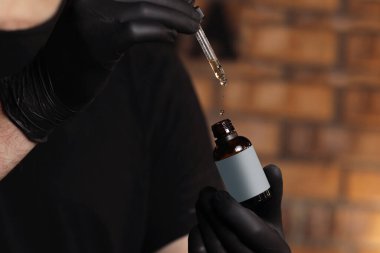 Damlatan cam şişe maketi. Yağlı damlalar koyu arkaplandaki kozmetik pipetinden düşer. E-sıvı damlatan şişeyi pipetin üzerine damlatarak açtım. Seçici odaklanma. metin için yer