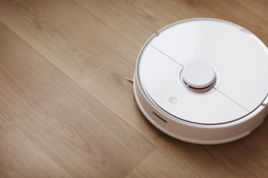 Robot elektrikli süpürge daireyi belli bir zamanda otomatik olarak temizliyor. Beyaz robot elektrikli süpürge. Ev temizliği. Akıllı ev. seçici odak.