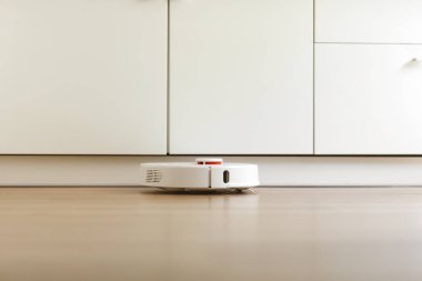 Robot elektrikli süpürge daireyi belli bir zamanda otomatik olarak temizliyor. Beyaz robot elektrikli süpürge. Ev temizliği. Akıllı ev. seçici odak.