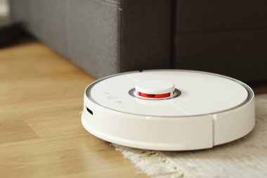 Robot elektrikli süpürge daireyi belli bir zamanda otomatik olarak temizliyor. Beyaz robot elektrikli süpürge. Ev temizliği. Akıllı ev. seçici odak.