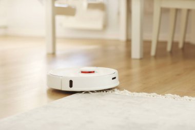 Robot elektrikli süpürge daireyi belli bir zamanda otomatik olarak temizliyor. Beyaz robot elektrikli süpürge. Ev temizliği. Akıllı ev. seçici odak.