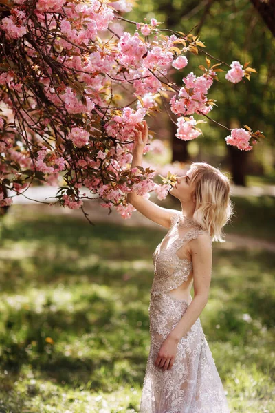 Menina bonita gosta do cheiro da árvore de floração. Retrato de mulher bonita com árvore de cereja florescente - menina inala o cheiro de flores com olhos fechados - primavera, natureza e conceito de beleza . — Fotografia de Stock