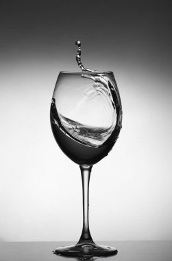 Gri arka planda beyaz şarap sıçraması. Bardağın silüeti. seçici odak.