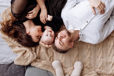 Güzel, genç bir aile evdeki yatakta yan yana yatıyor, anne, baba ve kız bebek, manzara çok güzel. Anneler günü, babalar günü, bebekler günü. Aile birlikte vakit geçiriyor. Aile görünüşü. seçici odak.