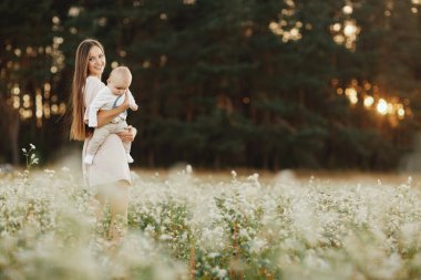 Mutlu çocuk ve annesi bir tarlada eğleniyor. Anne çocuğu kollarında tutuyor, ve çocuk sarılıyor. Anneler Günü. seçici odak.