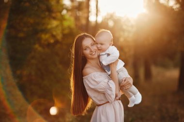 Mutlu çocuk ve annesi bir tarlada eğleniyor. Anne çocuğu kollarına alır, ve çocuk annesine sarılır ve onu öper. Anneler Günü. seçici odak.