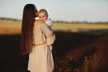 Mutlu çocuk ve annesi bir tarlada eğleniyor. Anne çocuğu kollarına alır, ve çocuk annesine sarılır ve onu öper. Anneler Günü. seçici odak.