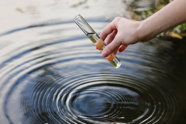 Water sample. Hand collects water to explore. Concept - water purity analysis, environment, ecology. Water testing for infections, permission to swim. selective focus, place for text