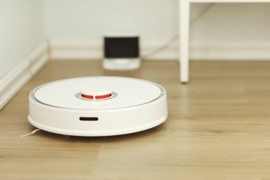 Beyaz robotik elektrikli süpürge. Robot doğrudan temizlik için ses komutlarıyla kontrol ediliyor. Modern akıllı temizlik teknolojisi. Dairenin temizlenmesi planlandı. seçici odak.