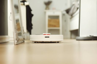 Beyaz robotik elektrikli süpürge. Robot doğrudan temizlik için ses komutlarıyla kontrol ediliyor. Modern akıllı temizlik teknolojisi. Dairenin temizlenmesi planlandı. seçici odak.