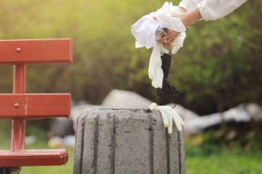 Kadın çöpe plastik çöp atıyor. Kadın eli parkta temizlik için çöp poşeti topluyor. Salgından sonra çöp toplama. seçici odak.
