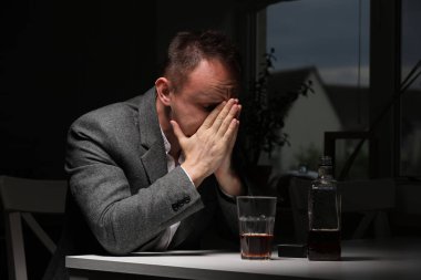 Mutfakta viski şişesi olan bir adam. Sarhoşluk ve alkolizm kavramı. Alkolik baba. Kederli, yorgun ve hasta bir adam tek başına içiyor. Duygusal bir deneyim. seçici odak.