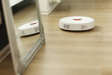 Beyaz robotik elektrikli süpürge. Robot doğrudan temizlik için ses komutlarıyla kontrol ediliyor. Modern akıllı temizlik teknolojisi. Dairenin temizlenmesi planlandı. seçici odak.