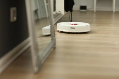 Beyaz robotik elektrikli süpürge. Robot doğrudan temizlik için ses komutlarıyla kontrol ediliyor. Modern akıllı temizlik teknolojisi. Dairenin temizlenmesi planlandı. seçici odak.