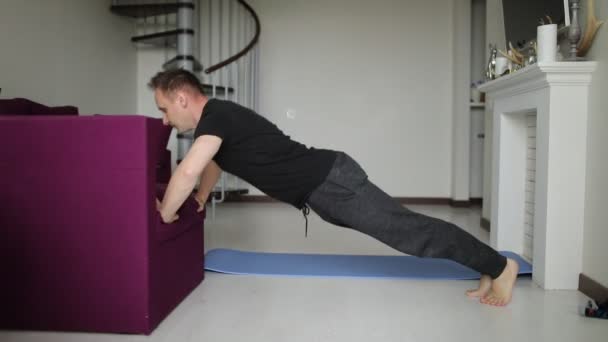 Un joven en forma hace flexiones en su sala de estar en casa. Deporte y estilo de vida saludable . — Vídeo de stock