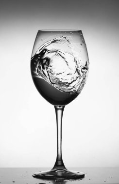 Cam şarap kadehinde bir damla su. Su parlak arka planda cama sıçrıyor. Şarap bardağına dökülen şeffaf sıvı. Yiyecek, nesne