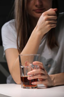 Oturan ve elinde viski ya da konyakla bardak tutan, alkol bağımlısı, depresyonda olan, alkol bağımlısı, kişisel sorunları olan güçlü bir kadın.