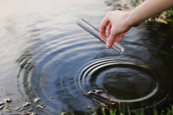 Scienziato e biologo idro-biologo preleva campioni d'acqua per l'analisi. La mano raccoglie l'acqua in una provetta. Concetto di inquinamento idrico stagno . — Foto Stock