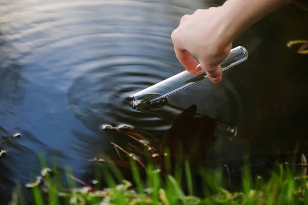 Naukowiec i biolog hydrobiolog pobiera próbki wody do analizy na zewnątrz. Ręka zbiera wodę do probówki. Koncepcja zanieczyszczenia wód stawu. — Zdjęcie stockowe
