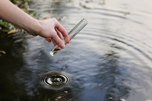 Naukowiec i biolog hydrobiolog pobiera próbki wody do analizy na zewnątrz. Ręka zbiera wodę do probówki. Koncepcja zanieczyszczenia wód stawu. — Zdjęcie stockowe
