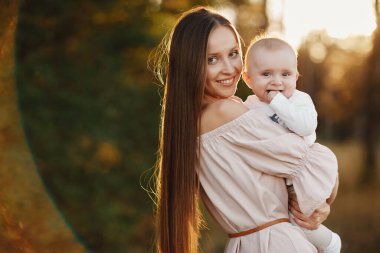 Mutlu çocuk ve annesi bir tarlada eğleniyor. Anne çocuğu kollarına alır, ve çocuk annesine sarılır ve onu öper. Anneler Günü. seçici odak.