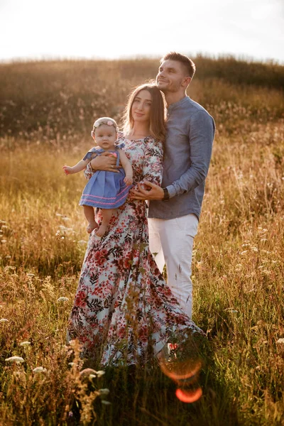 Mãe, pai e menina se divertindo ao ar livre na grama no dia de verão. mães, pais e bebês dia. Família feliz para uma caminhada . — Fotografia de Stock