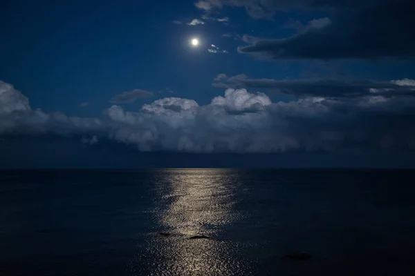 Dolunay ve denizde yansıma ile gece gökyüzü, güzel bulutlar.