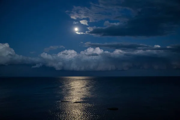 Dolunay ve denizde yansıma ile gece gökyüzü.