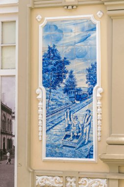 Funchal, Portekiz - 10 Kasım 2019: Portekiz yapımı teneke kaplamalı seramik seramik kaplama, hasır bir kızakla kayan bir tobogan binişi sunar.