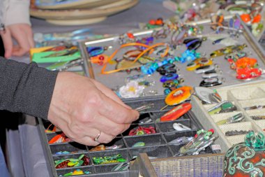 Kadın eli, el yapımı mücevherler, renkli cam desenler seçer..