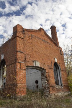 Mavi gökyüzüne karşı terk edilmiş eski tuğla sanayi binası.