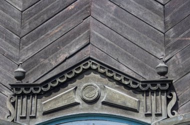 Arka planda oyulmuş platform bandı olan eski bir ahşap evin duvarı..