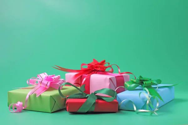 Gifts in boxes in holiday packaging on a green background, place for text or congratulations.