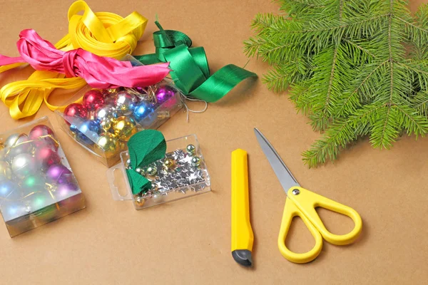A small set of materials and tools for decorating Christmas tree branches for the holiday, colored balls, ribbons, branches, scissors, top view.