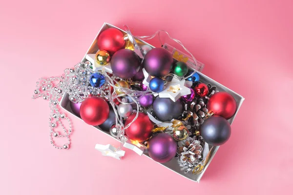 Christmas tree toys in a box on a pink background, top view, close-up, place for text or congratulations. — Stock Photo, Image