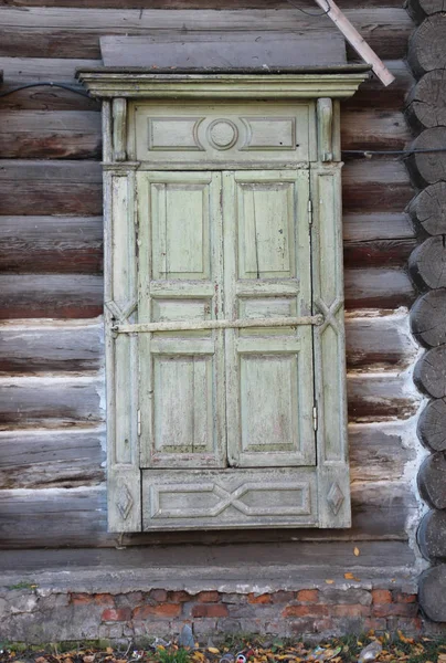 Alte geschnitzte Fenster mit Rollläden an einem alten Blockhaus, Nahaufnahme. — Stockfoto