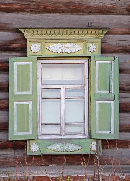 Antique παράθυρο με παντζούρια και σκαλιστά platband σε ένα σπίτι κούτσουρο. — Φωτογραφία Αρχείου