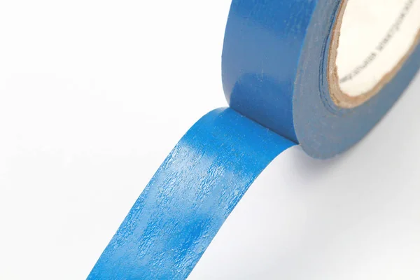 Rol van blauwe polymeer isolerende tape met een kleverige laag op een witte achtergrond, plaats voor tekst, close-up. — Stockfoto