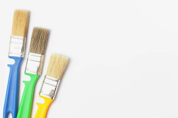 Verf penselen van verschillende kleuren op een witte achtergrond close-up, platte lay, plaats voor tekst. — Stockfoto