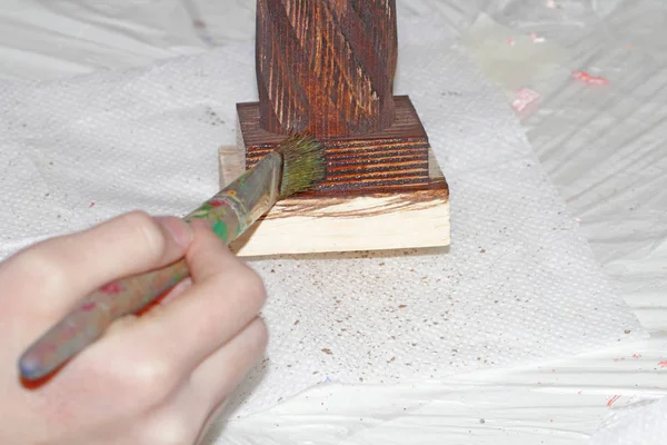 El maestro pinta una pieza de madera con un cepillo de impregnación de color . — Foto de Stock