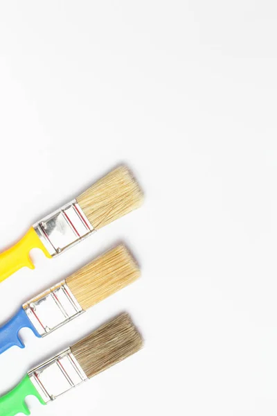 Close-up of color paint brushes on a white background, place for text, vertical frame, flat lay. — 스톡 사진