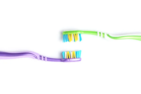 Dua sikat gigi dengan gagang warna yang berbeda saling berhadapan di latar belakang putih, close-up . — Stok Foto