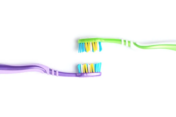 Dos cepillos de dientes con asas de diferentes colores uno frente al otro sobre un fondo blanco, primer plano . — Foto de Stock