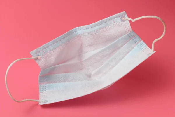 Pembe arka planda tıbbi maske, insan virüslerine karşı etkili bir koruma.