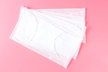 Pembe arka planda bir yığın tıbbi maske. Yakın plan, düz alan. Coronavirüs ve diğer bulaşıcı hastalıklarla mücadele kavramı..