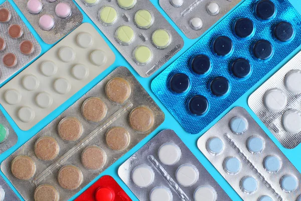 Orvosi tabletták csomagolásban minta kék háttér közelkép, lapos laikus. — Stock Fotó