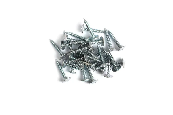 A bunch of sheet metal screws on a white background close-up. — Stock Photo, Image