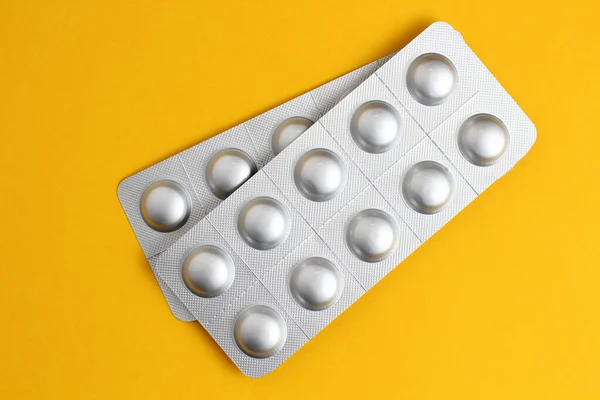 Medical pills in packs on a orange background close-up, flat lay.