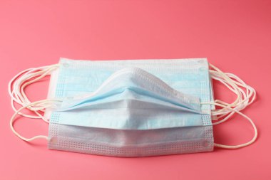 Pembe arka planda birkaç tıbbi maske, insan koronavirüsüne karşı etkili bir koruma, yakın plan..