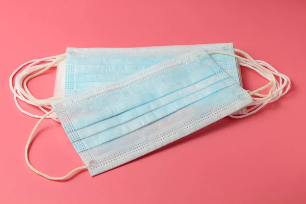 Pembe arka planda birkaç tıbbi maske, insan koronavirüsüne karşı etkili bir koruma, yakın plan..